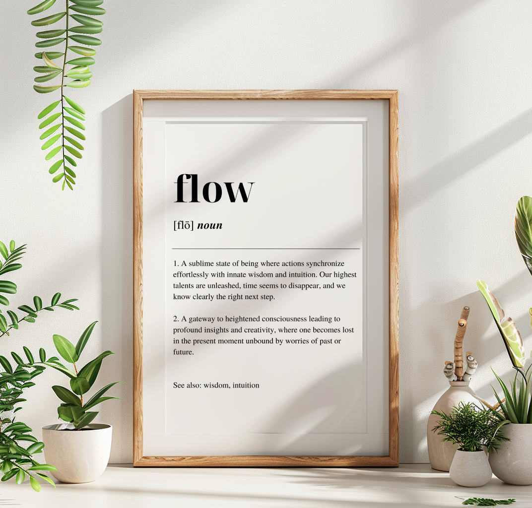 A fine art print with the word 'Flow' defined in a minimalist style, displayed in a wooden frame, with a green foliage and potted plant to the left.