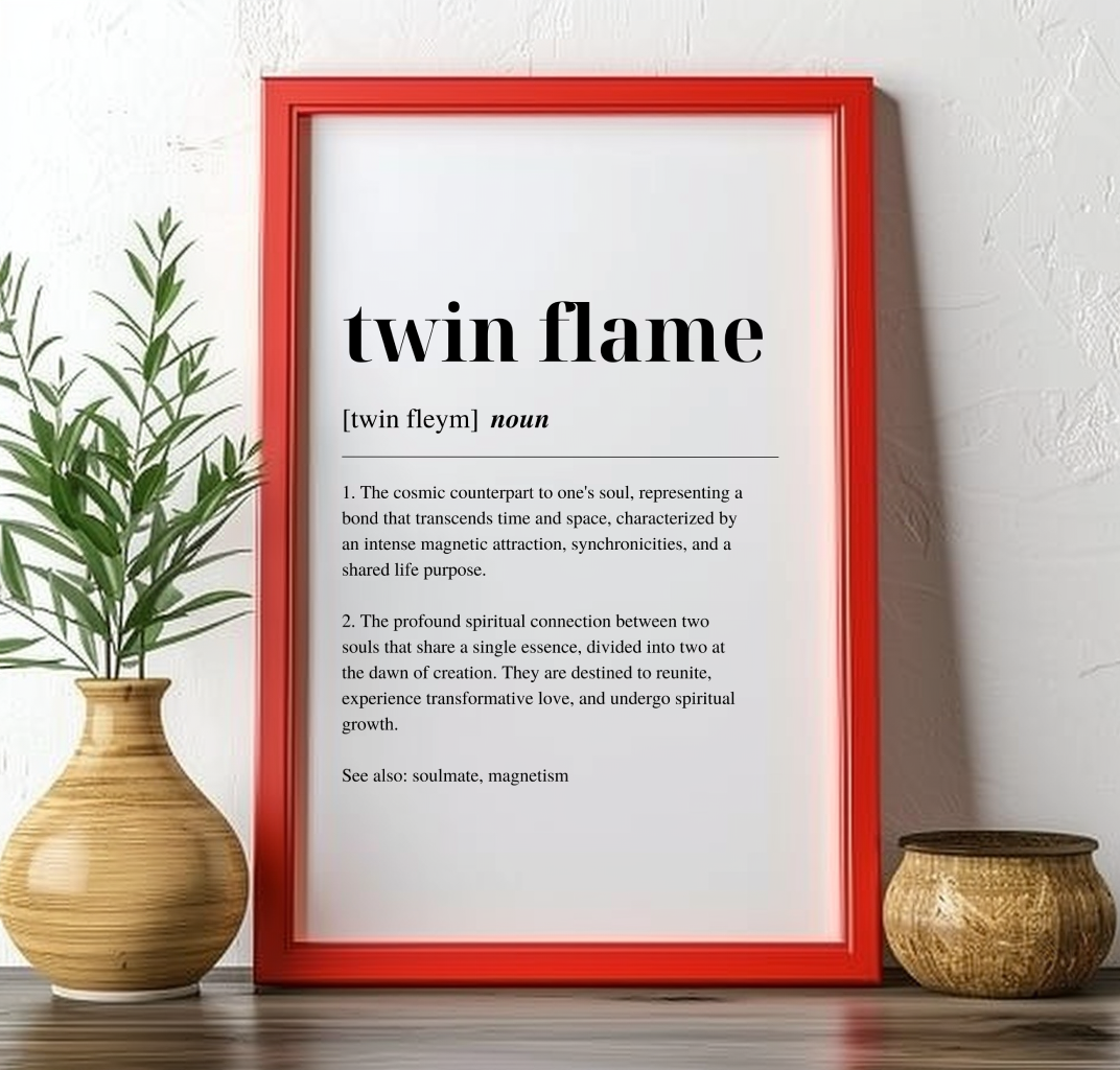 Red framed poster on a mantlepiece with inspirational definition art text for the word and meaning of Twin Flame. The frame is next to a plant in a vase