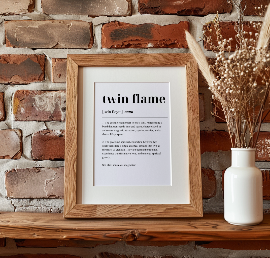 Wooden framed poster on a mantlepiece with inspirational definition art text for the word and meaning of Twin Flame. The frame is next to a dried plant in a vase