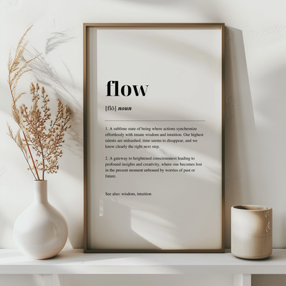 A fine art print with the word 'Flow' defined in a minimalist style, displayed in a wooden frame, with a dried  plant to the left.