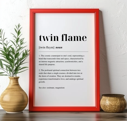 Red framed poster on a mantlepiece with inspirational definition art text for the word and meaning of Twin Flame. The frame is next to a plant in a vase